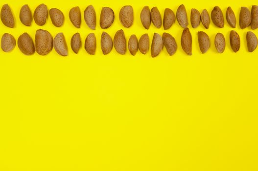 In shell raw almonds on yellow background with copy space