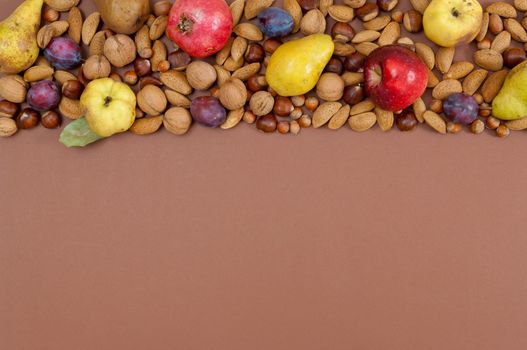 Organic autumn fruits and nuts on brown background with copy space