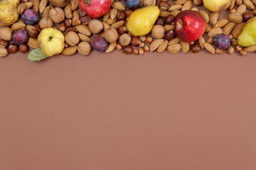 Organic autumn fruits and nuts on brown background with copy space
