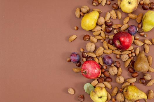 Organic autumn fruits and nuts on brown background with copy space