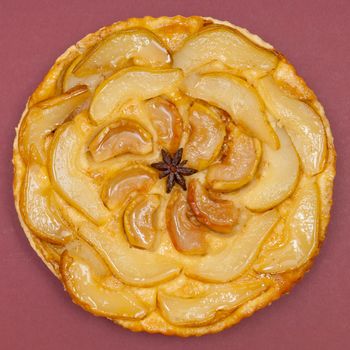 Whole tarte Tatin apple and pear tart pie isolated on claret background with copy space