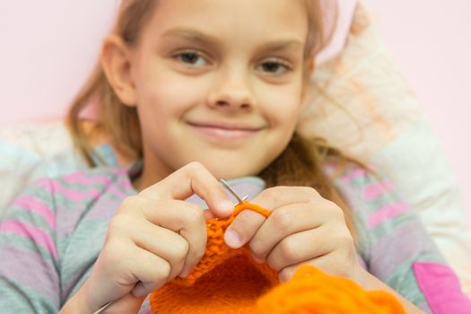 Happy girl knits on the needles, and looked into the frame, the camera focuses on the spokes