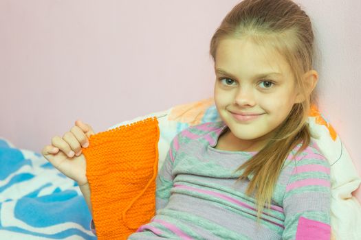 Girl shows a scarf tied on needle