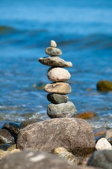 A stone tower on a stone beach with
 blue background