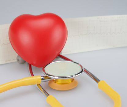 Medical stethoscope with red heart and electrocardiogram  on white background.