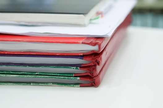 Notebook and  and stack of report book on desk with office background.