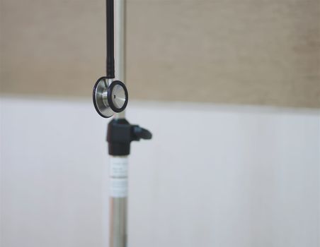 Black stethoscope hanging on iv stand in patient room  at hospital.                          