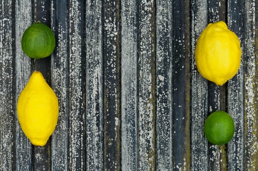 Lemon and lime arrangement on old black textured metal surface