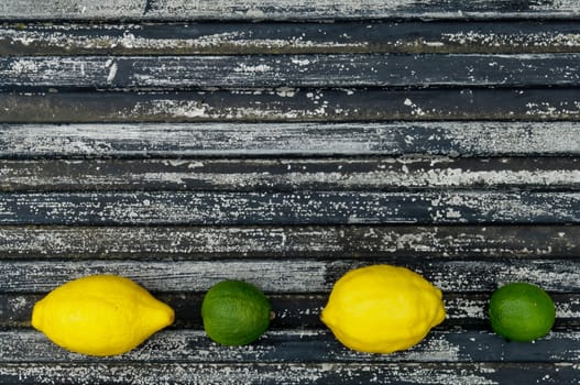 Lemon and lime arrangement on old black textured metal surface