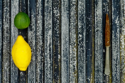 Lemon and lime arrangement on old black textured metal surface