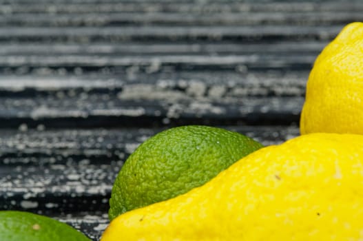 Lemon and lime arrangement on old black textured metal surface