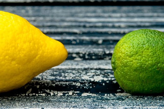 Lemon and lime arrangement on old black textured metal surface