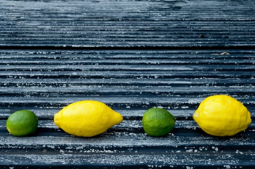 Lemon and lime arrangement on old black textured metal surface