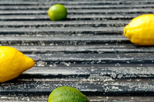 Lemon and lime arrangement on old black textured metal surface