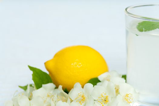 Lemonade with fresh lemon and mint leaves with copy space white flowers decoration