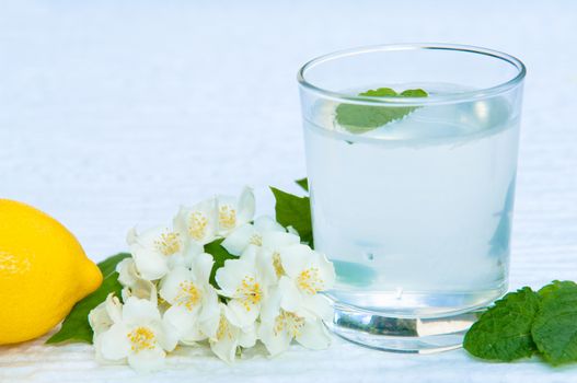 Lemonade with fresh lemon and mint leaves with copy space white flowers decoration