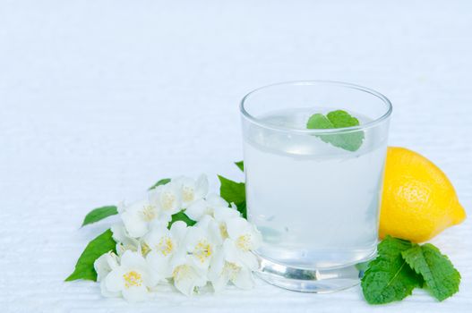 Lemonade with fresh lemon and mint leaves with copy space white flowers decoration