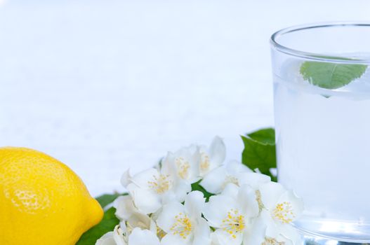 Lemonade with fresh lemon and mint leaves with copy space white flowers decoration