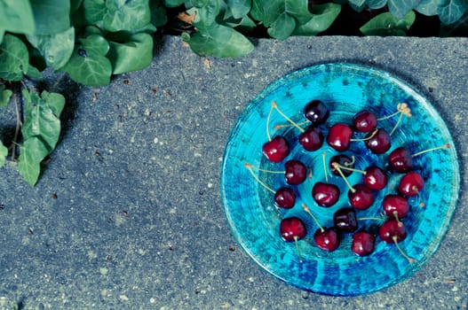 Delicious ripe cherry  on blue plate on grey stone flat lay Healthy fruit eating Top view