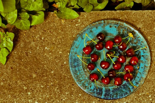 Delicious ripe cherry  on blue plate on grey stone flat lay Healthy fruit eating Top view