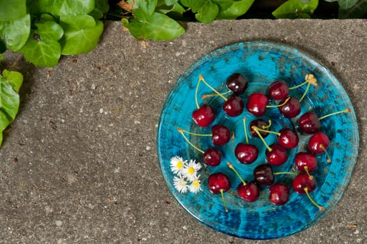 Delicious ripe cherry  on blue plate on grey stone flat lay Healthy fruit eating Top view