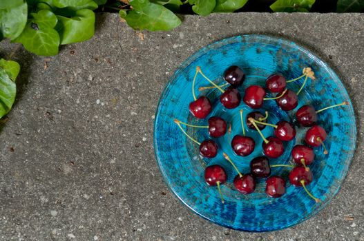 Delicious ripe cherry  on blue plate on grey stone flat lay Healthy fruit eating Top view