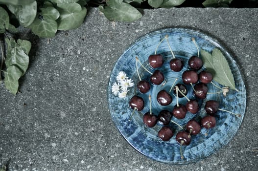 Delicious ripe cherry  on blue plate on grey stone flat lay Healthy fruit eating Top view