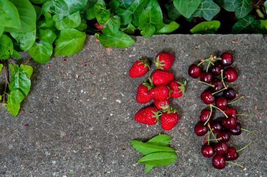 Delicious ripe strawberry and cherry on grey stone flat lay Healthy fruit eating Top view