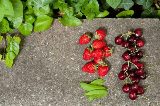 Delicious ripe strawberry and cherry on grey stone flat lay Healthy fruit eating Top view