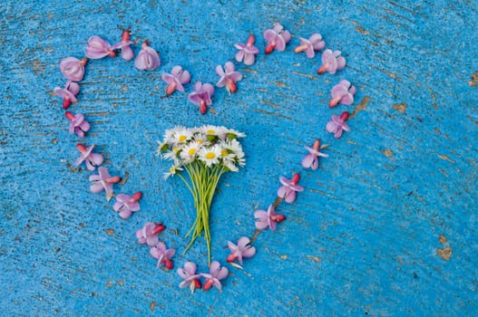 Heart shape formed from pink flowers on an old texture light blue background  turquoise background vintage