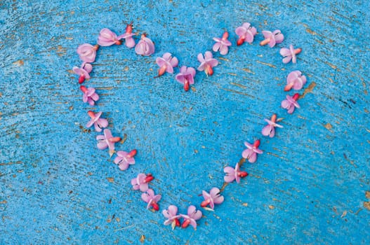 Heart shape formed from pink flowers on an old texture light blue background  turquoise background vintage