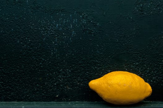 Lemon in front of rough textured black background metal background