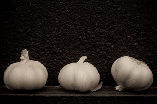 Garlic in front of rough textured black background metal background