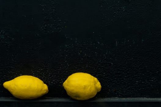 Lemon in front of rough textured black background metal background