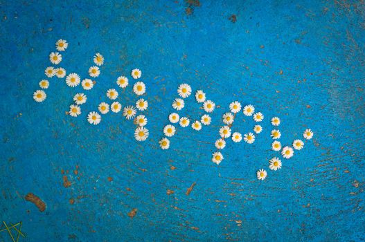 The word Happy written of daisy flowers on a textured, aged, light blue background. top view with copy space