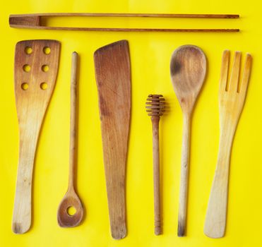 Old wooden spoons and stirrers on yellow background, kitchen utensils