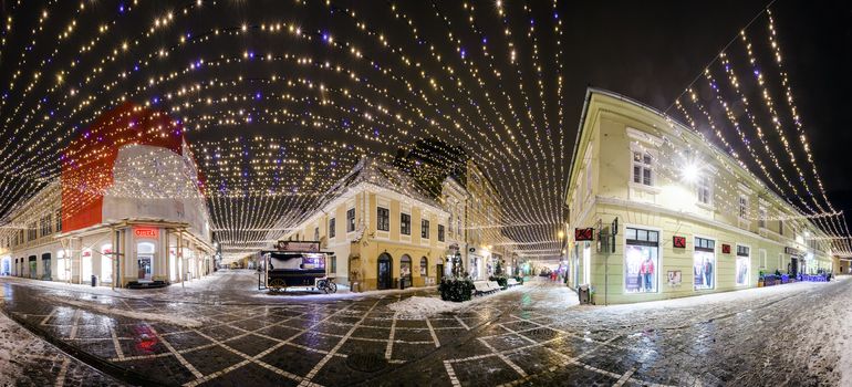 BRASOV, ROMANIA - 15 DECEMBER 2016: Panoramic night view of Republic Street decorated for winter hollidays with  Christmas lights in Brasov old city center, Romania