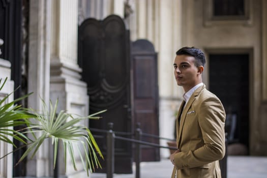 Elegant attractive young man outdoor wearing business suit, in European city