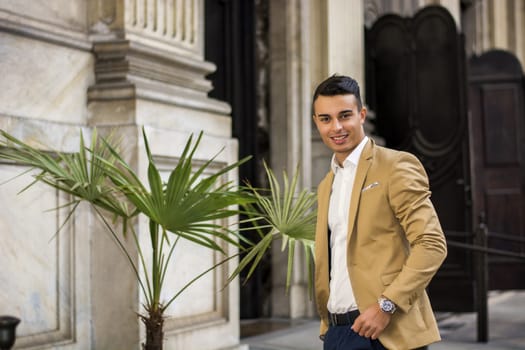 Elegant attractive young man outdoor wearing business suit, in European city