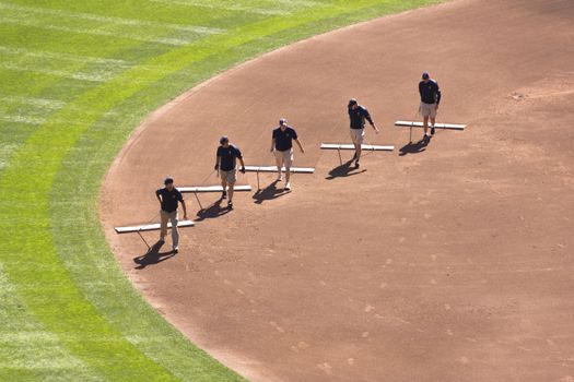 Minneapolis, MN - September 15, 2012: Five men clean a baseball diamond between innings at Target Field.