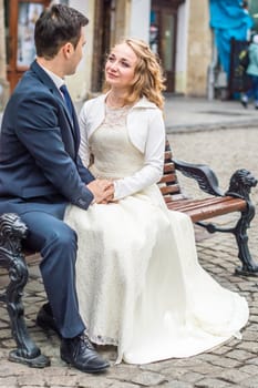 newly-weds sit on the bench in the city