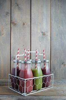 Flavoured smoothies in bottles in a rack over a wooden background