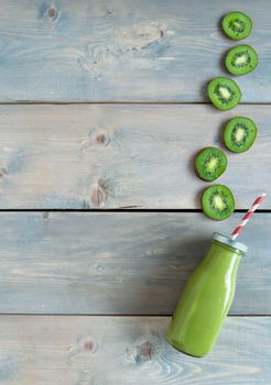 Kiwi flavoured smoothie in a bottle over a wooden background with copyspace