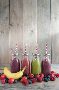 Flavoured smoothies in bottles in a rack over a wooden background with copyspace