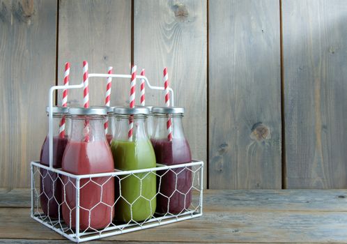 Flavoured smoothies in bottles in a rack over a wooden background with copyspace