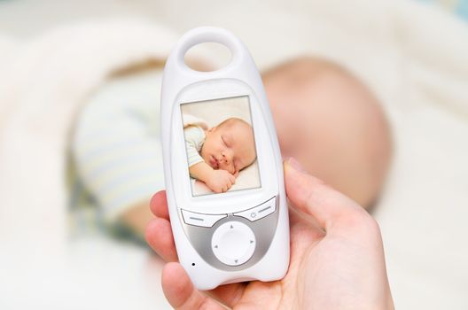 Hand holding video baby monitor for security of the baby