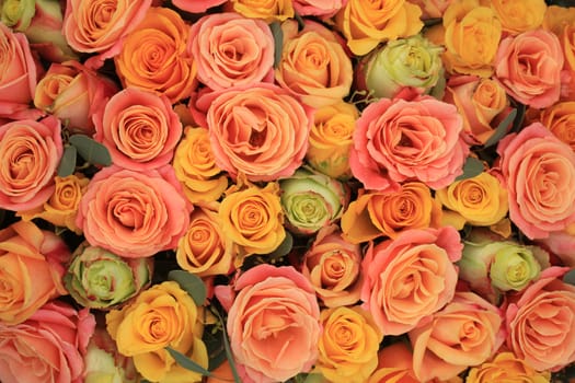 Yellow, orange and pink roses in a floral arrangement at a wedding