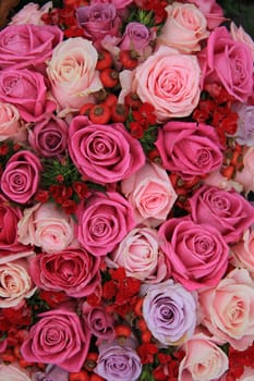 Bridal flower arrangement in various shades of pink and purple, mixed with red berries