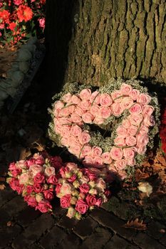Heart shaped sympathy or funeral flowers near a tree