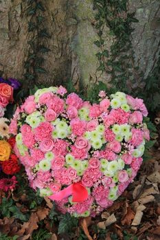 Heart shaped sympathy or funeral flowers near a tree